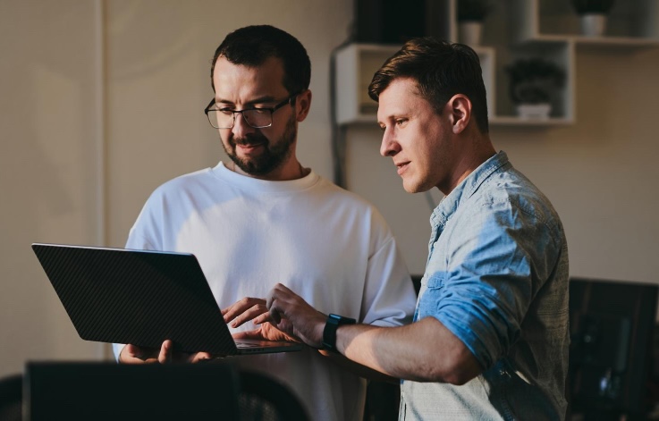 Zwei Software-Entwickler arbeiten gemeinsam am Laptop an ihrem Code